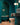 Bathroom with dark green or turquoise tiled walls, a freestanding bathtub that is the same color as the tiles tucked behind an archway, and a toilet.